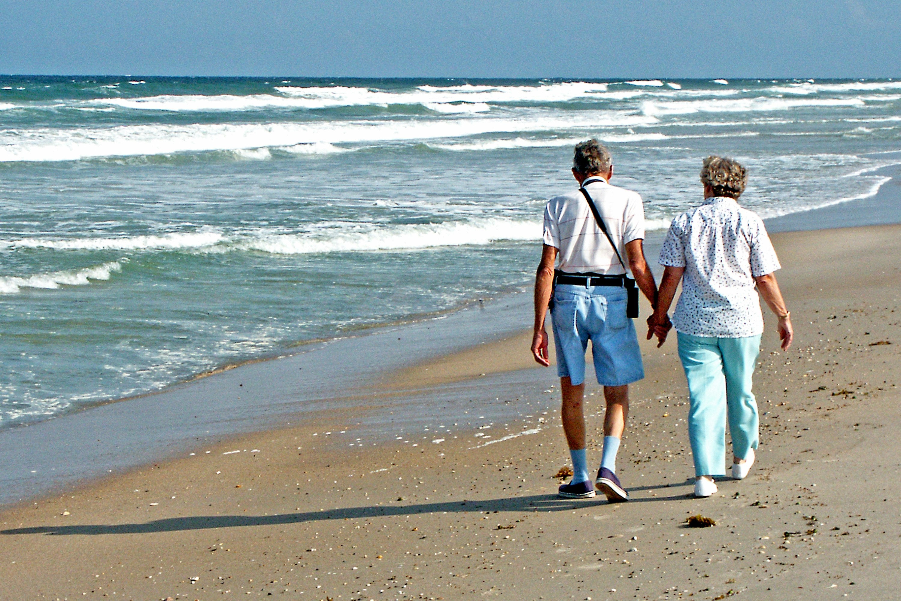 Happy couple walking hand in hand on the beach